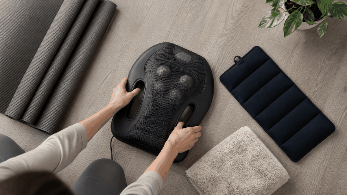Back massager with black textured casing and rounded massage nodes, shown with accessories to Ease Lower Back Pain